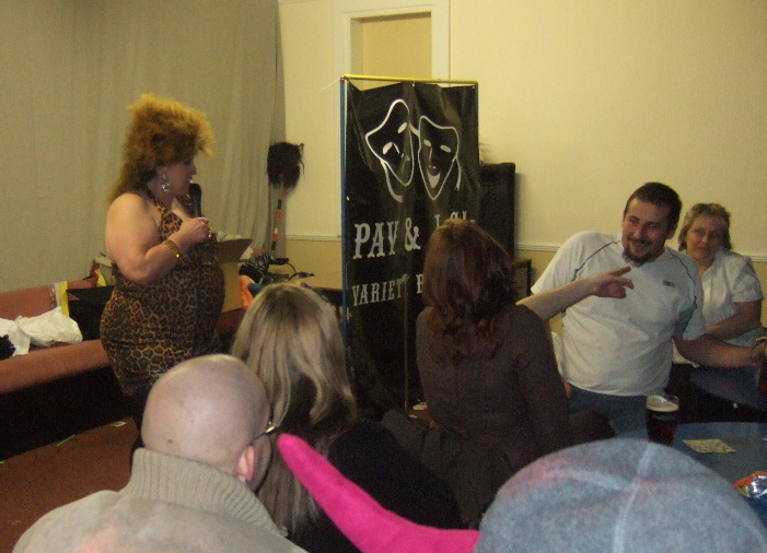 Comedienne Cristine Coles live on stage at Potters Langley Mill with a banner for Pav and JC's Variety Roadshow in the background.